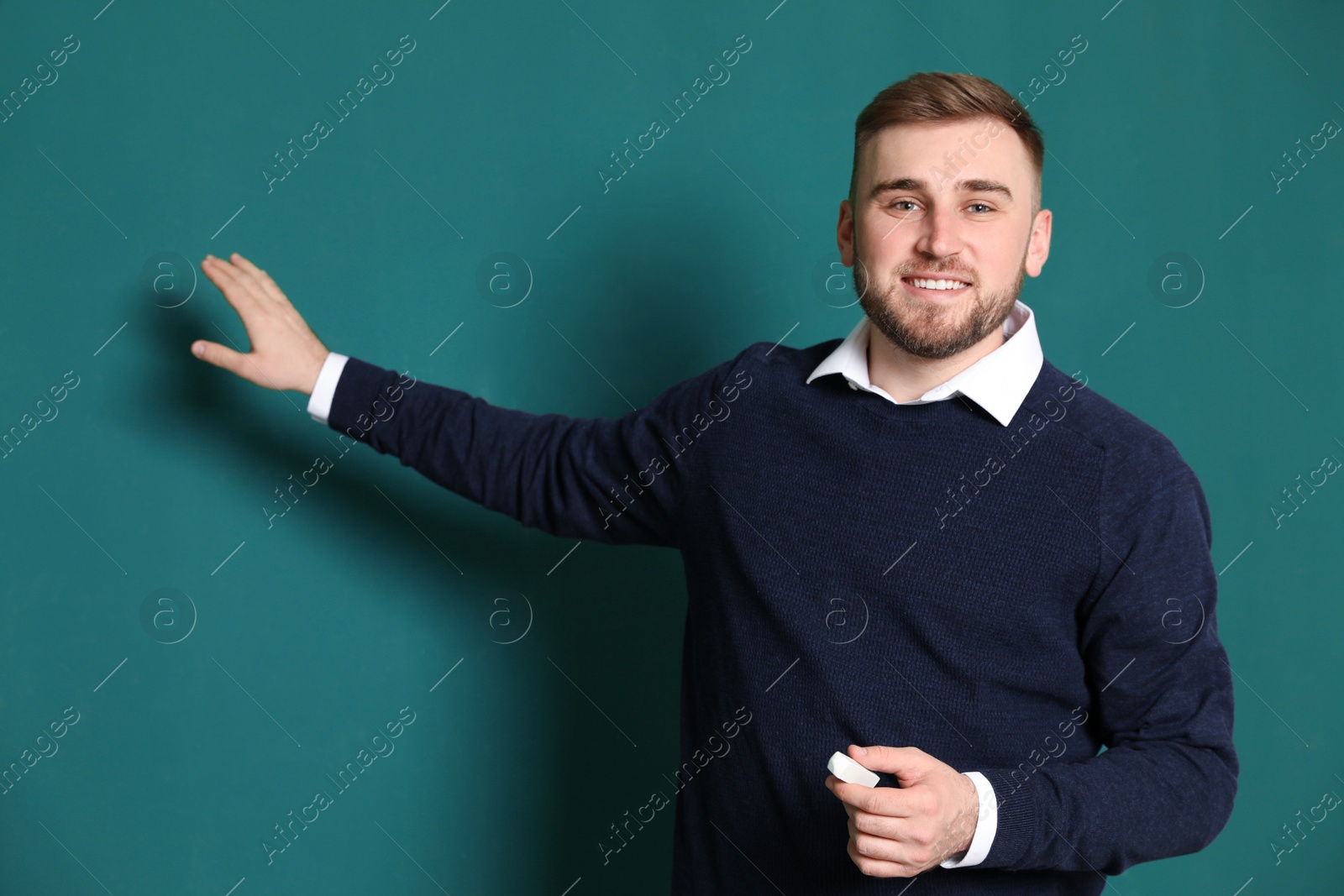 Photo of Portrait of young teacher with chalk on green background