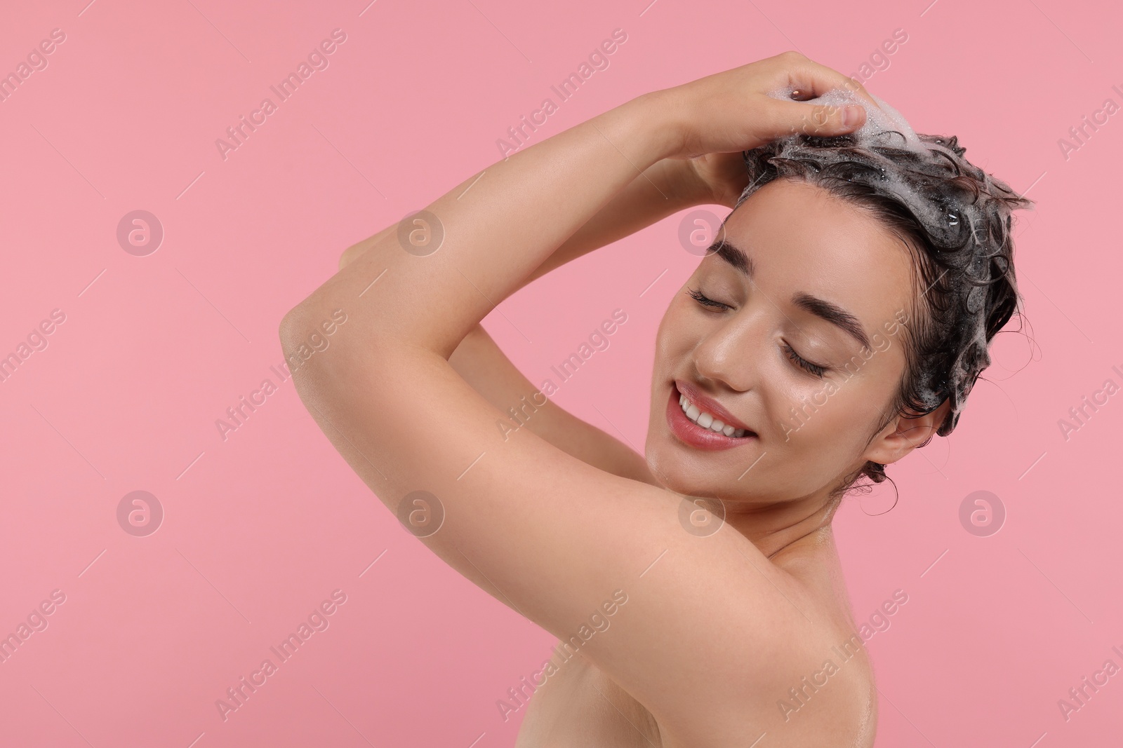 Photo of Beautiful happy woman washing hair on pink background. Space for text