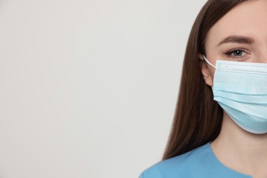 Nurse with medical mask on white background, closeup. Space for text