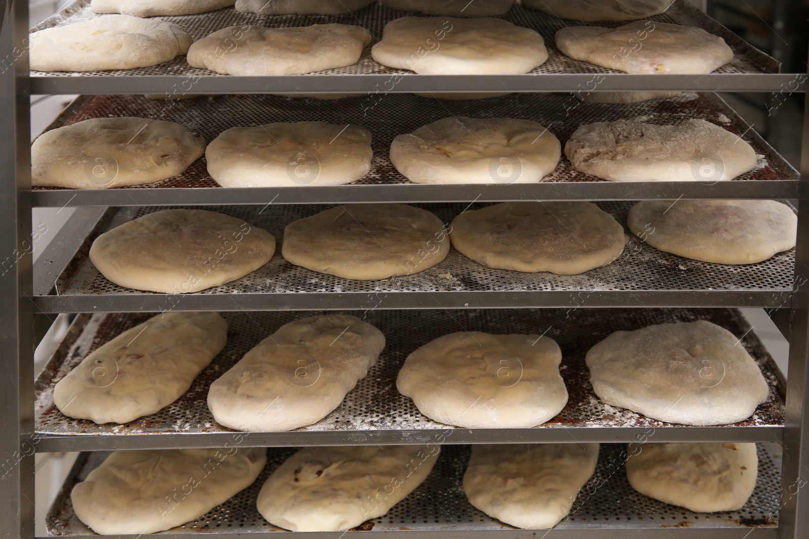 Photo of Rack with different unbaked pastries in workshop