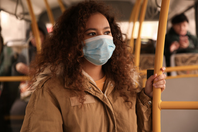 African-American woman with disposable mask on bus. Virus protection