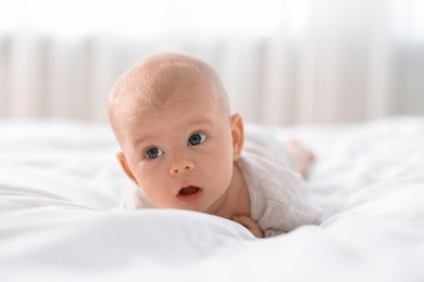 Photo of Cute little baby lying on white sheets