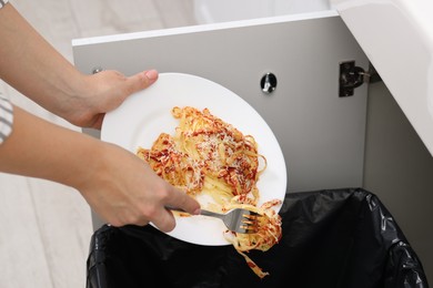 Woman throwing pasta into bin indoors, closeup