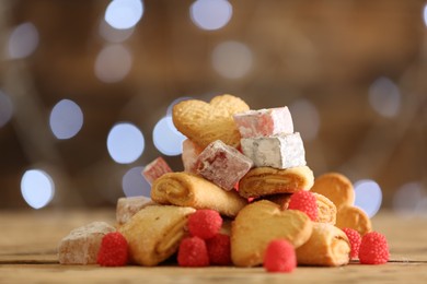 Photo of Delicious cookies and candies on wooden table against blurred background, closeup