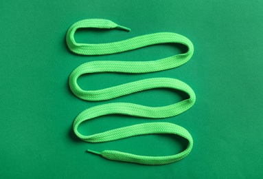 Photo of Shoelace on green background, top view. Stylish accessory