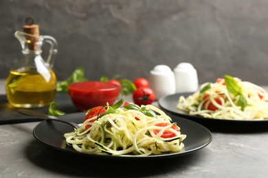 Photo of Delicious zucchini pasta with cherry tomatoes and basil served on light grey table