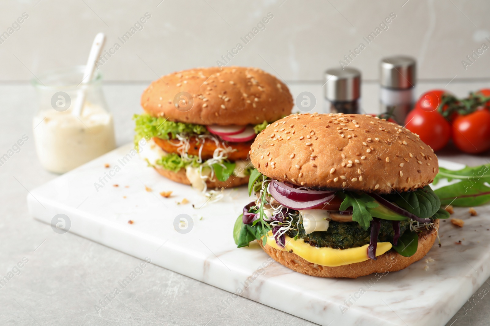 Photo of Board with tasty vegetarian burgers on table