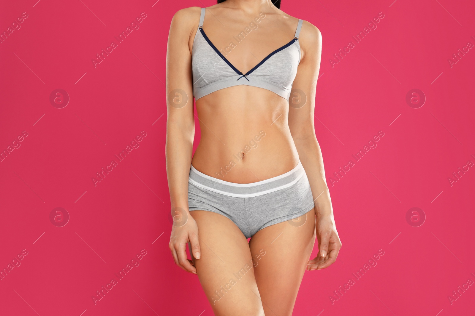 Photo of Young woman in grey sportive underwear on pink background, closeup