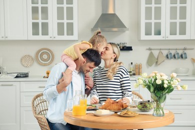 Photo of Happy family having fun during breakfast in kitchen