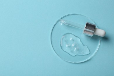 Photo of Pipette with cosmetic serum on light blue background, top view. Space for text