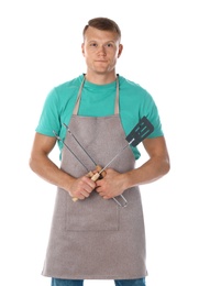 Man in apron with barbecue utensils on white background