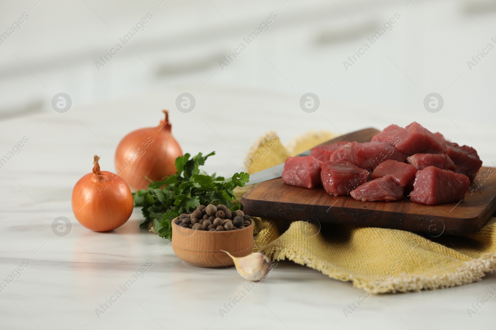 Photo of Raw beef meat with parsley and onion on white table, closeup