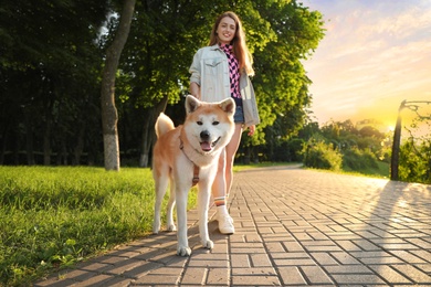 Photo of Young beautiful woman walking her adorable dog in park on sunny day