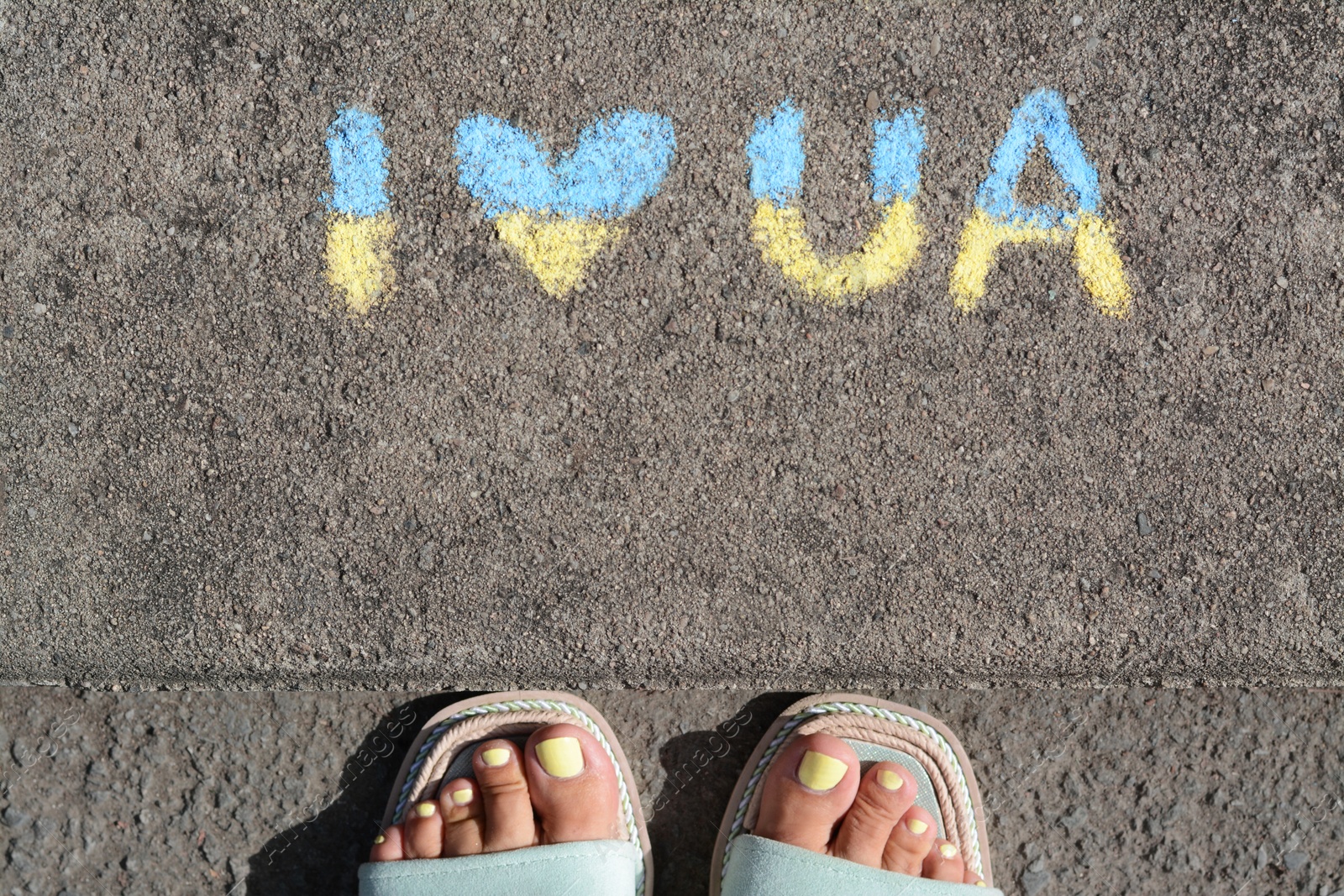 Photo of Woman near inscription I love Ukraine drawn by blue and yellow chalk on asphalt, top view