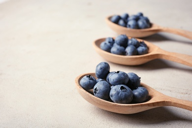 Photo of Wooden spoons and juicy blueberries on color table