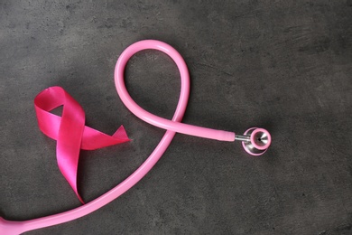 Photo of Pink ribbon with stethoscope on dark background. Breast cancer concept