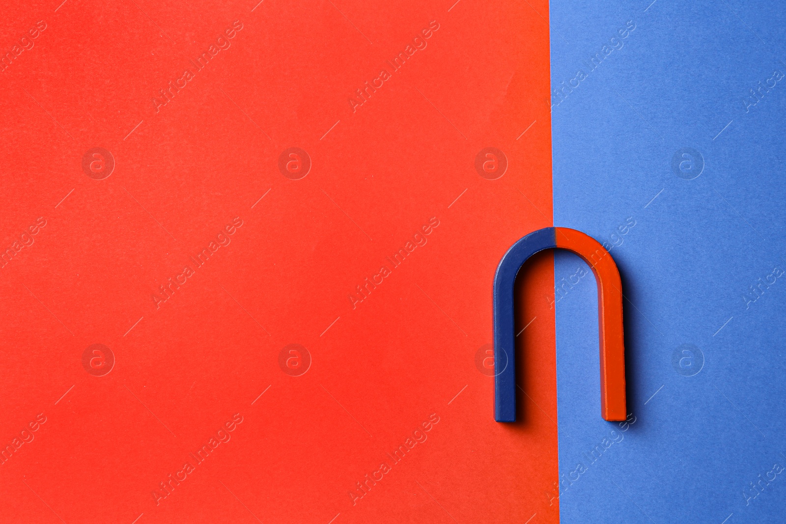 Photo of Red and blue horseshoe magnet on color background, top view. Space for text