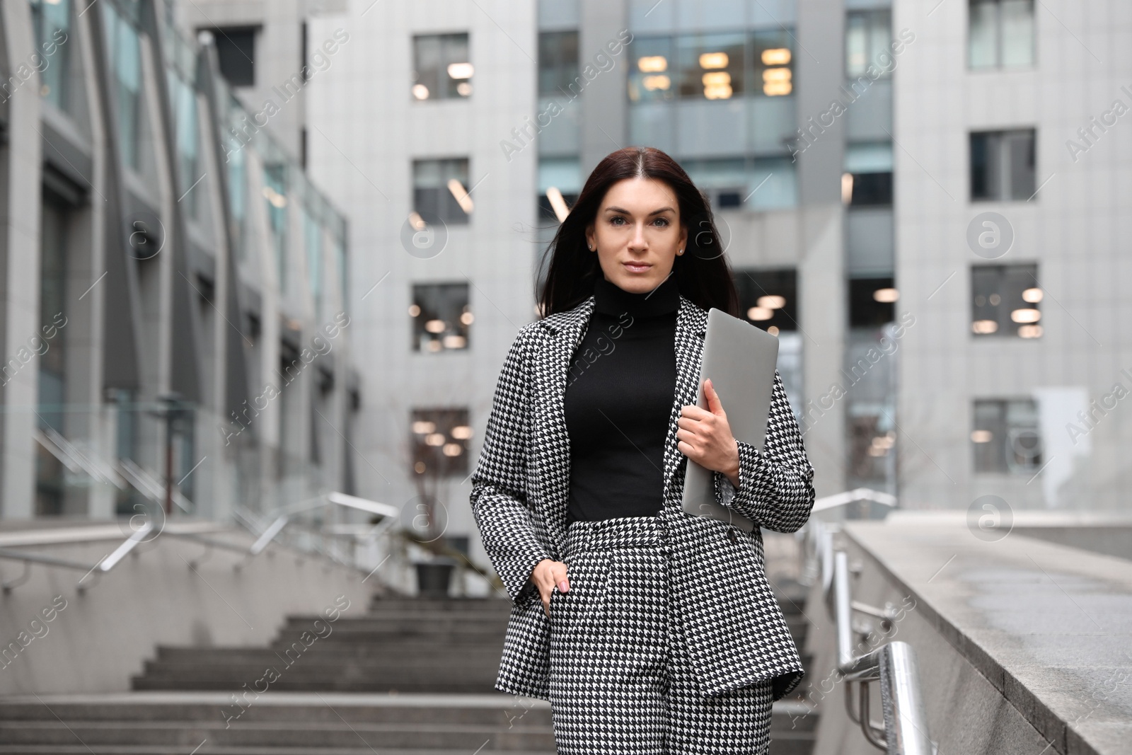 Photo of Beautiful woman in stylish suit with laptop outdoors. Space for text