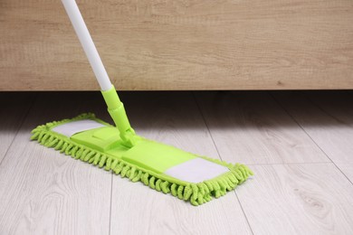 Photo of Cleaning dirty wooden floor with mop indoors. Space for text