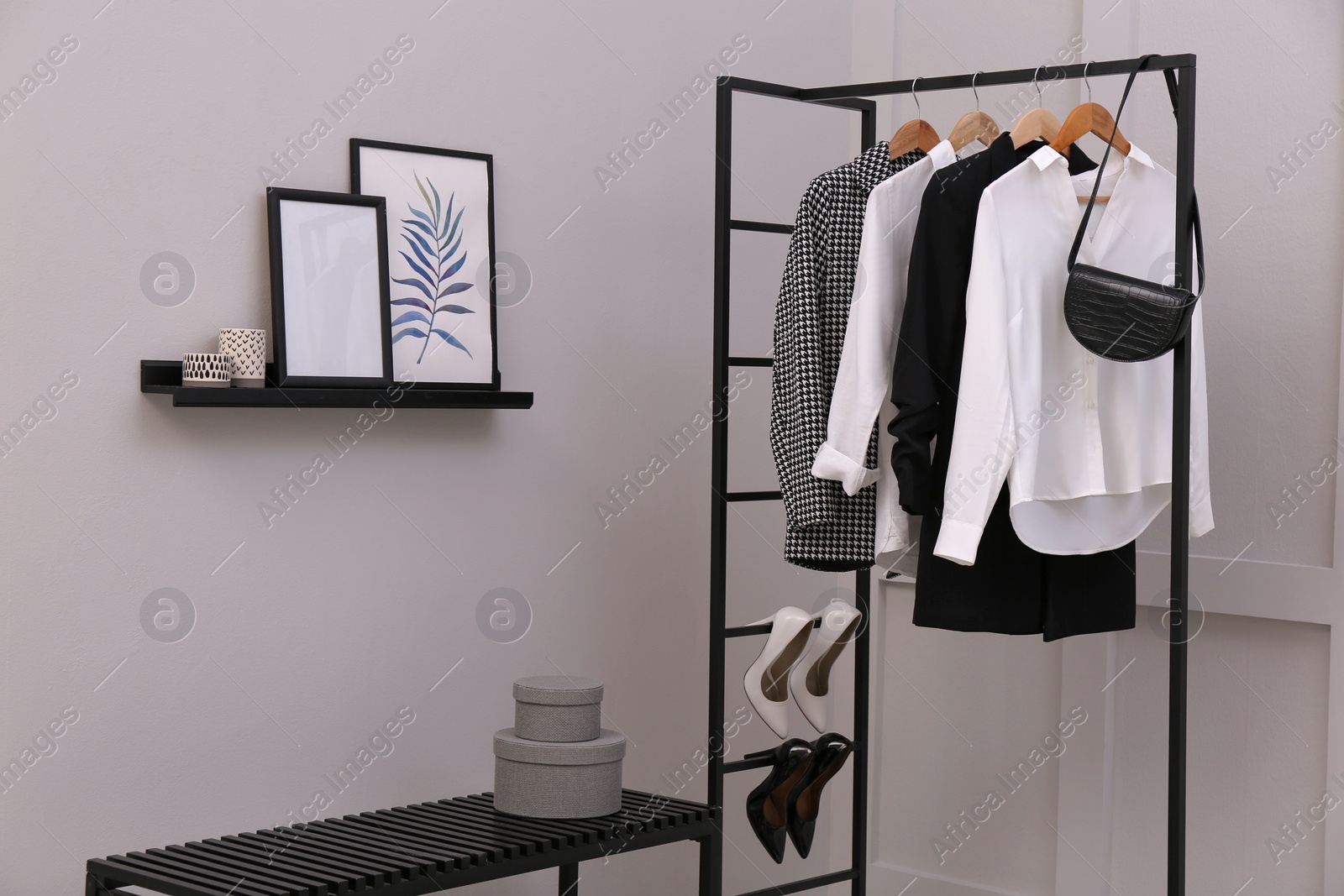 Photo of Rack with stylish women's clothes and bench in dressing room