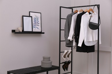 Rack with stylish women's clothes and bench in dressing room