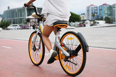 Photo of Young woman riding bicycle on lane in city, closeup