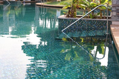 Photo of Outdoor swimming pool with metal rail and steps. Luxury resort