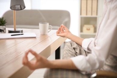 Photo of Woman meditating at workplace in office, closeup