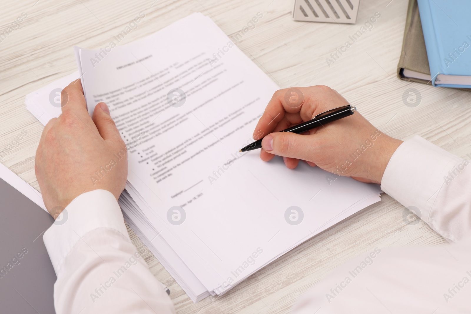 Photo of Man signing document at wooden table, closeup