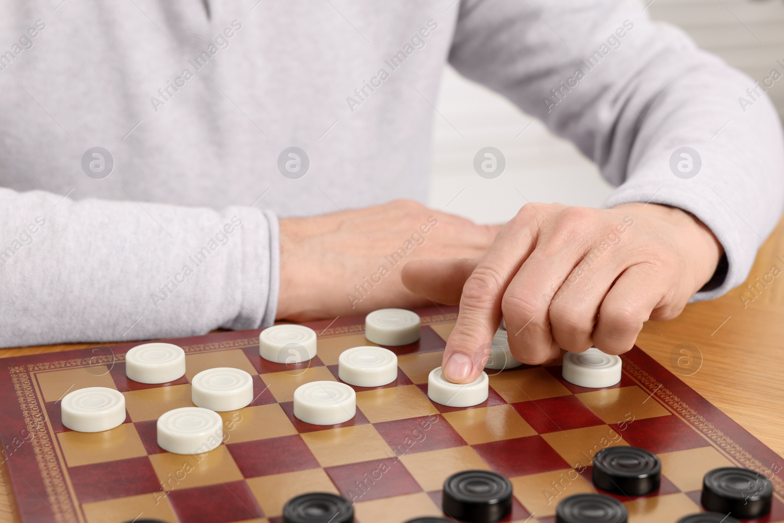 Photo of Playing checkers. Senior man thinking about next move at table, closeup