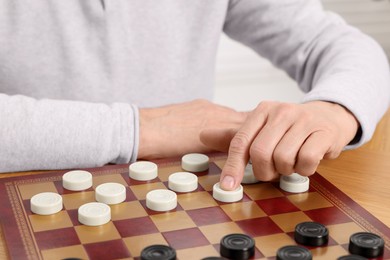 Photo of Playing checkers. Senior man thinking about next move at table, closeup