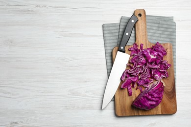 Photo of Tasty fresh shredded red cabbage and knife on white wooden table, flat lay. Space for text