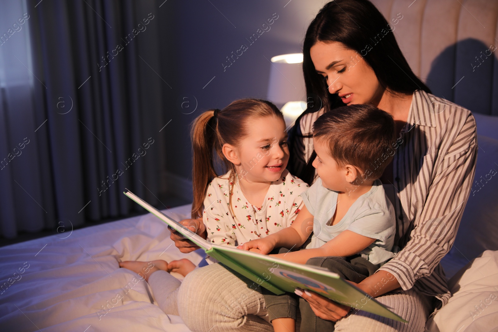 Photo of Mother reading bedtime story to her children at home