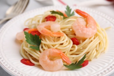 Tasty spaghetti with shrimps, chili pepper and parsley on plate, closeup