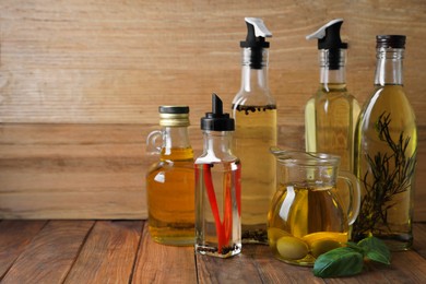 Photo of Many different cooking oils on wooden table, space for text