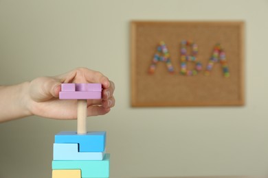 Photo of Child playing with toy pyramid indoors, closeup. ABA therapy concept