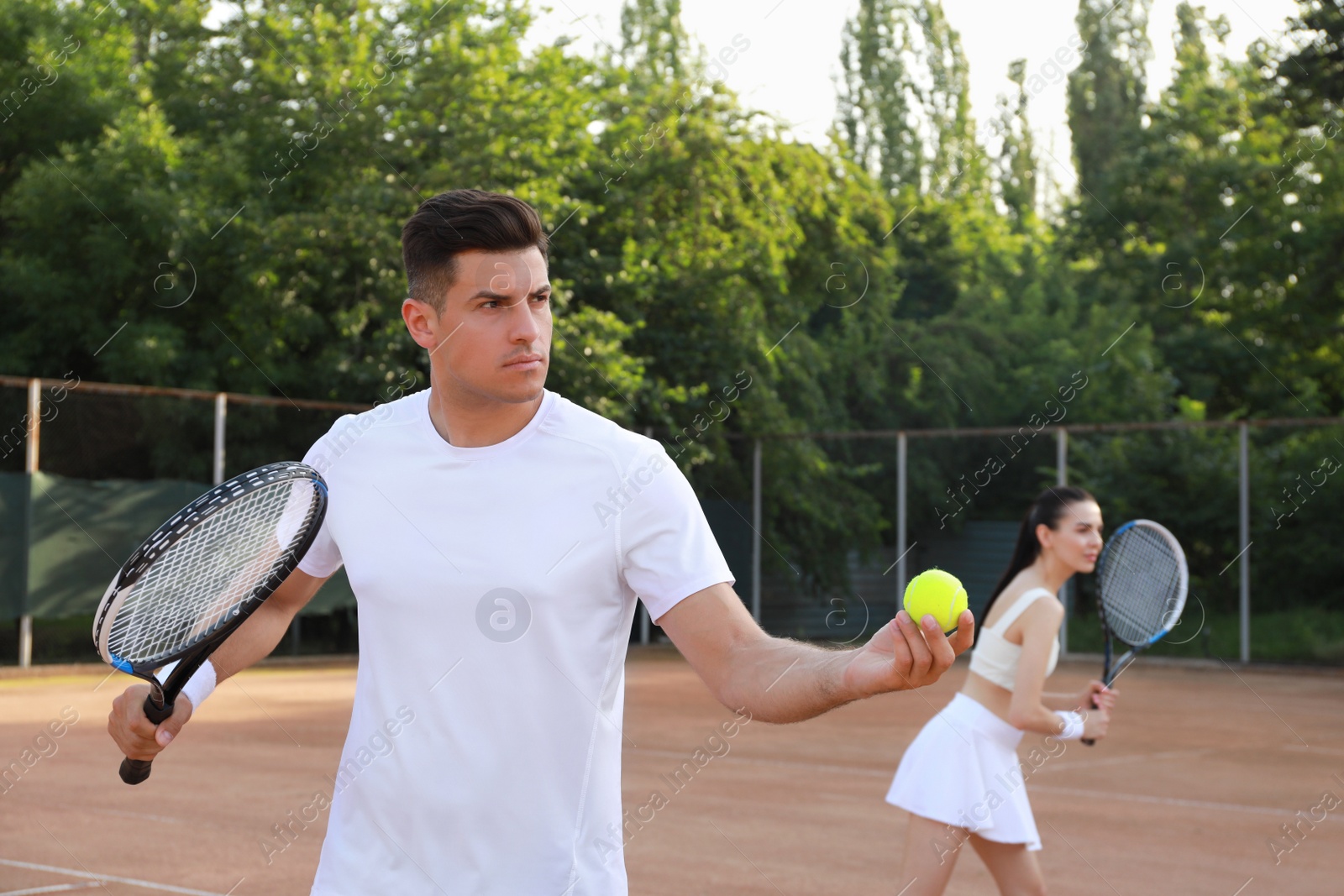 Photo of Couple playing tennis at court on sunny day