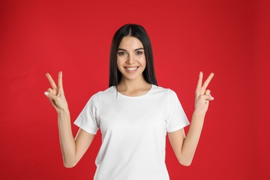 Woman showing number four with her hands on red background