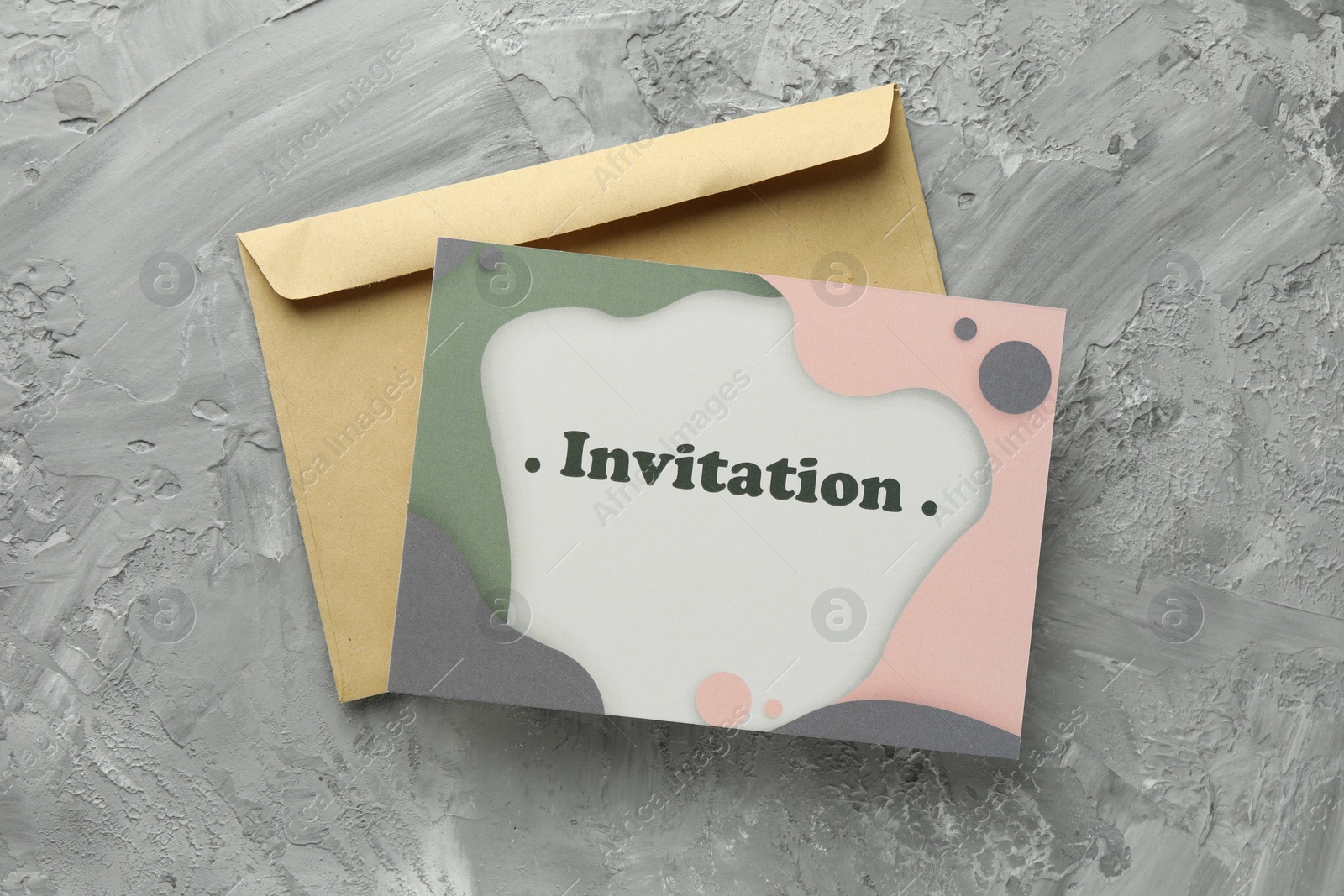 Photo of Beautiful card with word Invitation and envelope on grey table, flat lay