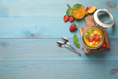 Photo of Delicious mango jelly with fresh fruits on light blue wooden table, flat lay. Space for text