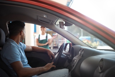 Man in car speaking with gas station worker