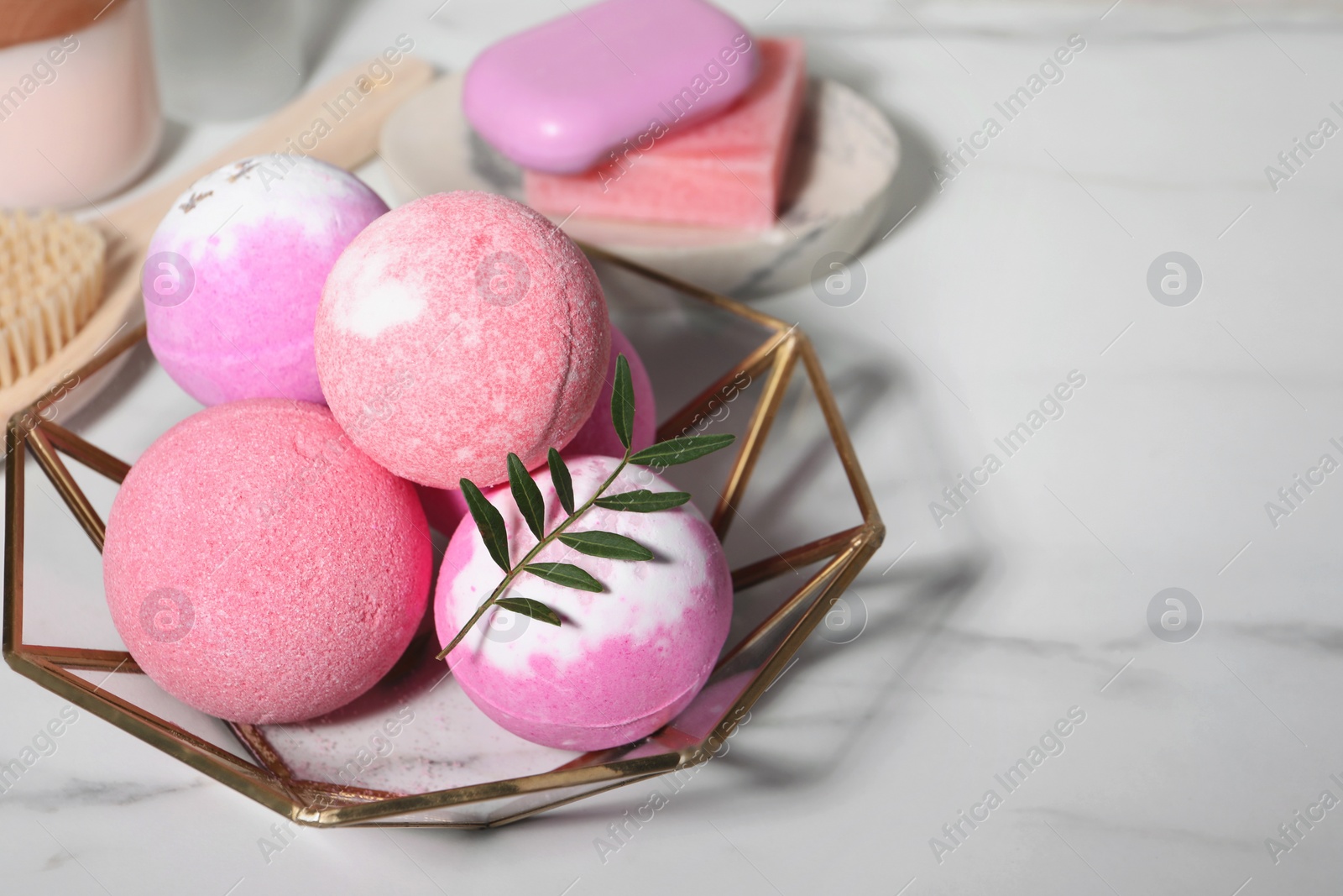 Photo of Beautiful aromatic bath bombs and green twig on white marble table, space for text