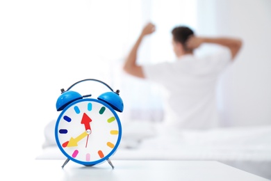 Photo of Analog alarm clock and blurred man on background. Time of day