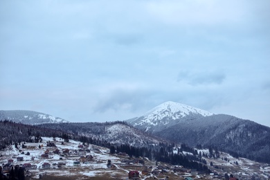 Photo of Winter landscape with mountain village near conifer forest