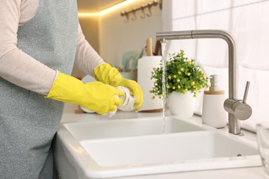 Housewife washing glass in kitchen sink, closeup