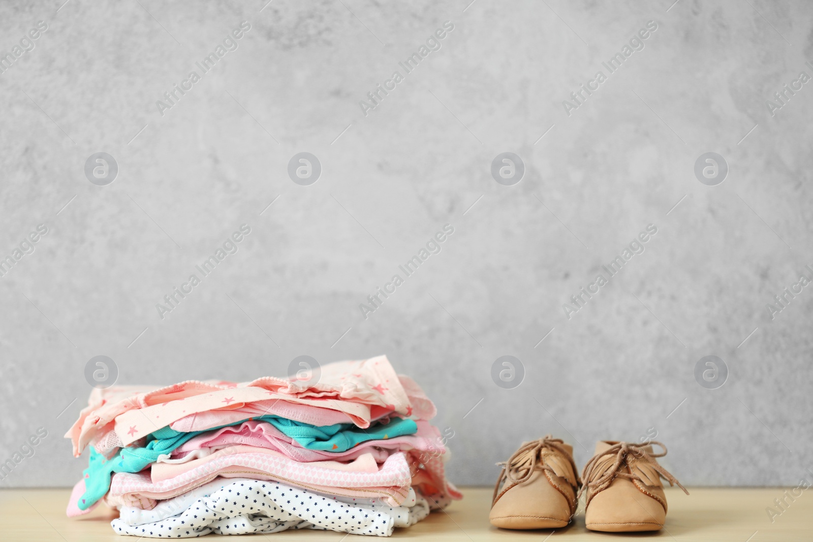 Photo of Pile of baby clothes and shoes on table