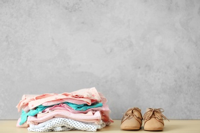 Pile of baby clothes and shoes on table