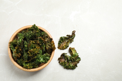 Photo of Tasty baked kale chips on grey marble table, flat lay. Space for text