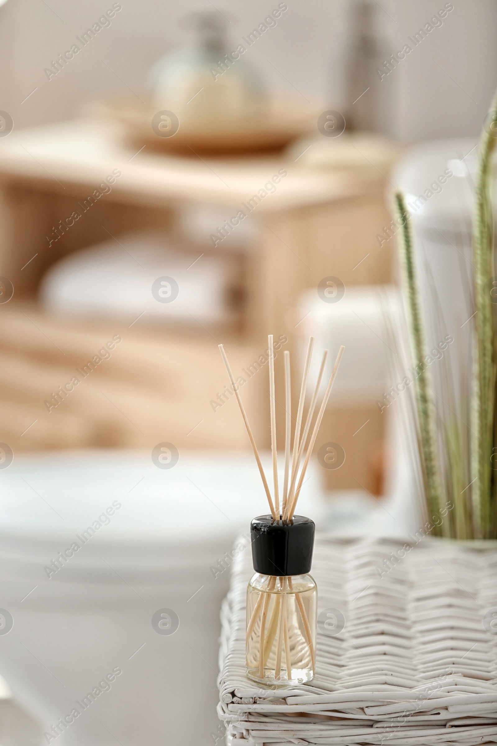 Photo of Aromatic reed air freshener on table against blurred background