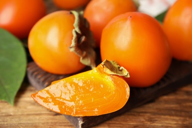 Photo of Delicious fresh persimmons on wooden table, closeup